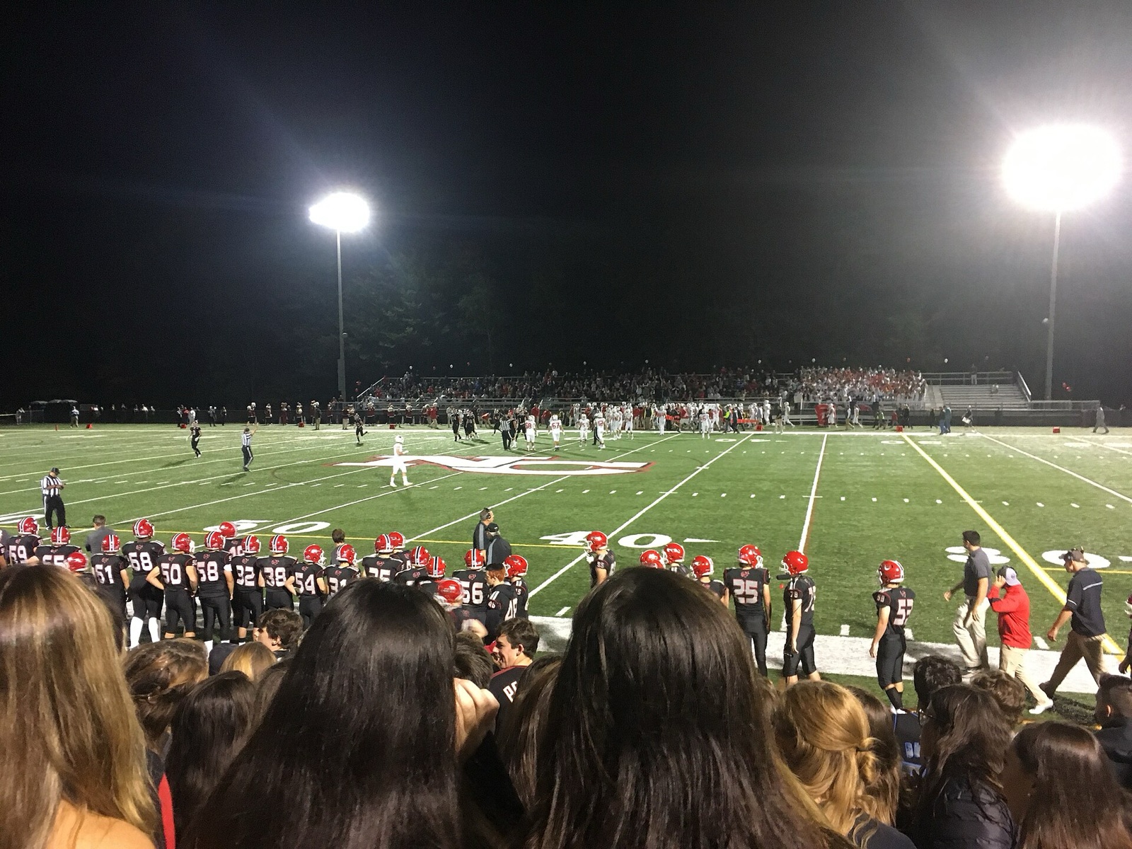 Students in the stands at a night high school football game