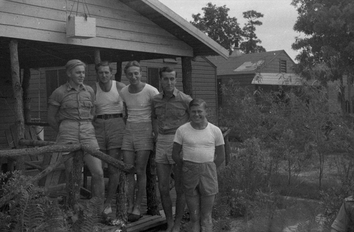 Men outside a wooden barracks in a 1944 photo labeled as the Camp Blanding prisoner of war camp.